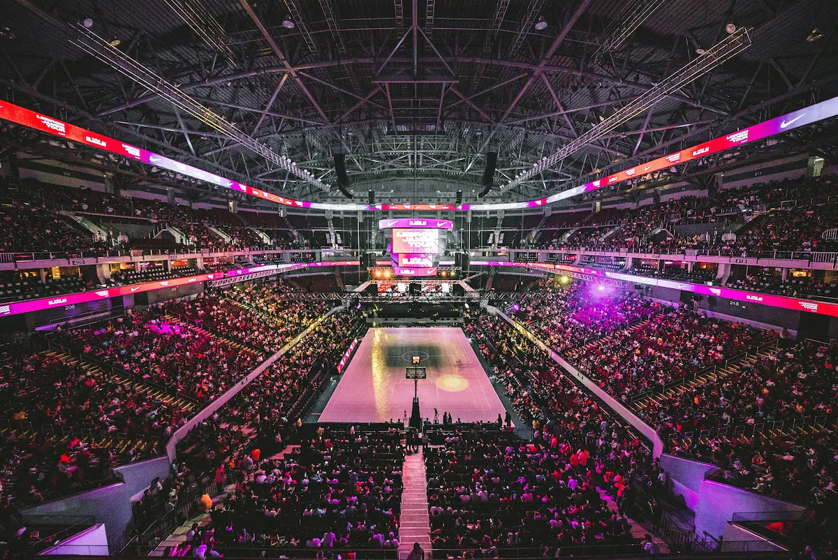 Cheering crowds pack a basketball arena in anticipation of the game.